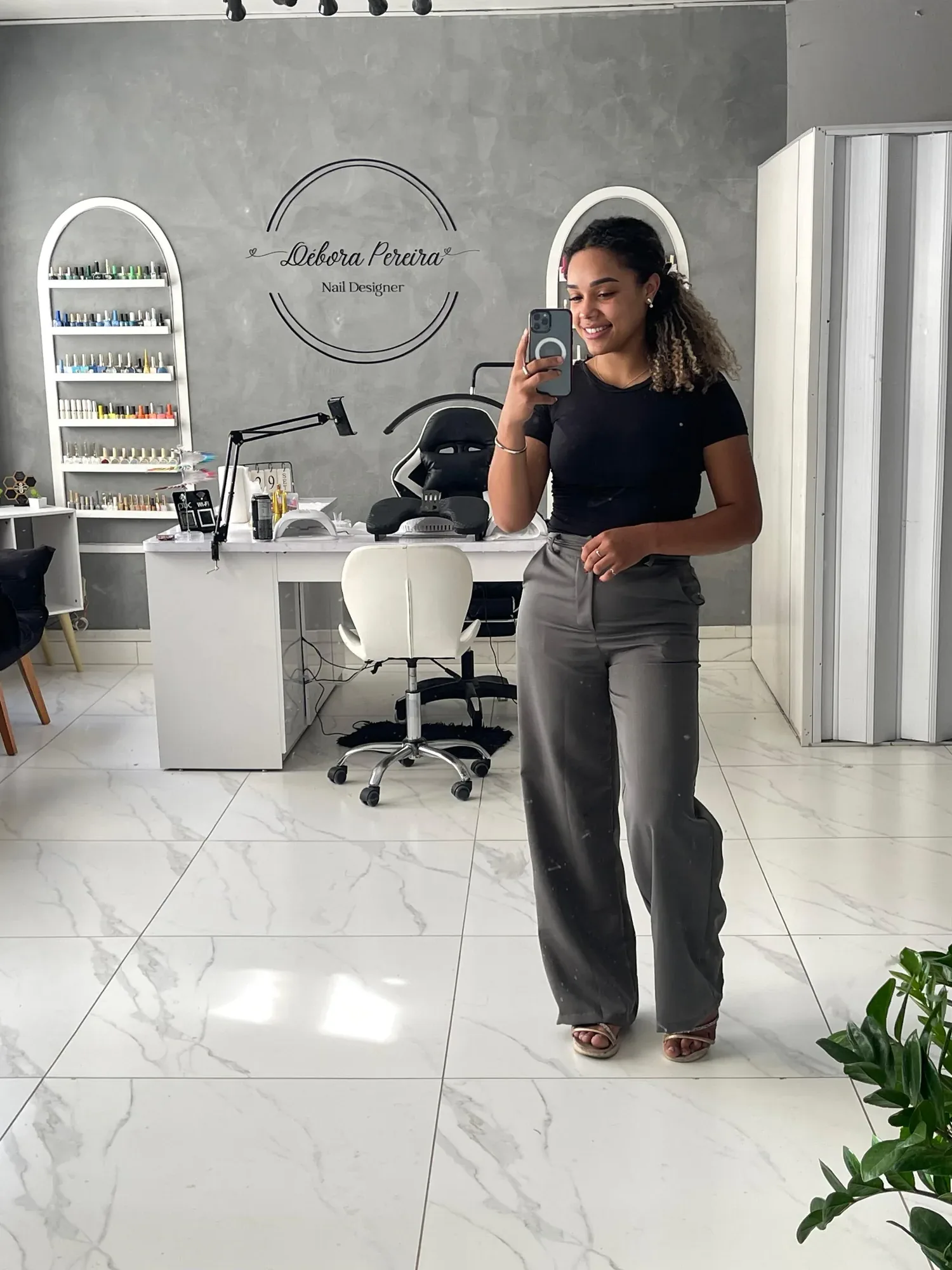 Deborah no estúdio, em frente ao letreiro com a logo dela