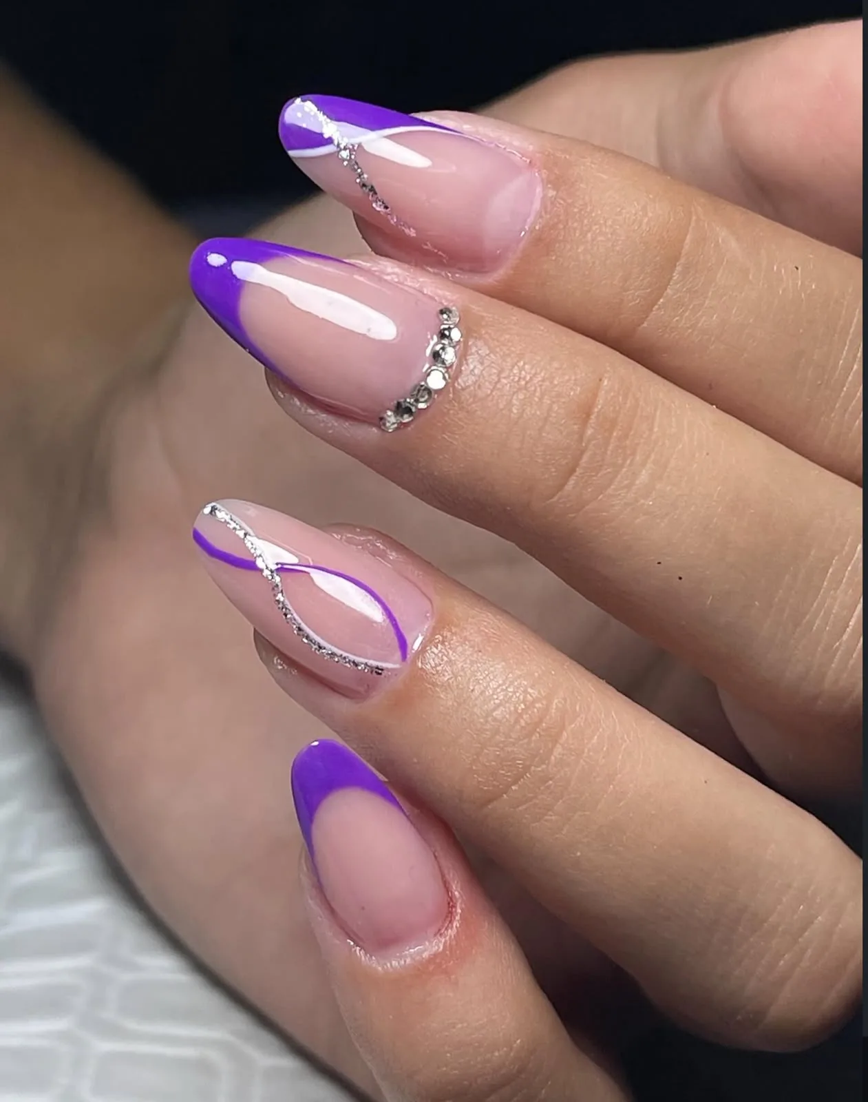 Unhas amendoadas com decoração roxa e pedraria